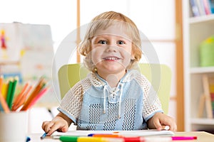 Cute child little boy drawing with felt-tip pen in kindergarten classroom