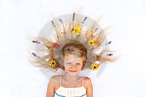 Cute child with long blond hair stylized with lavender and gerbera floral decoration, shot from birds perspective