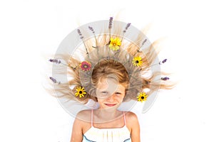 Cute child with long blond hair stylized with lavender and gerbera floral decoration, shot from birds perspective