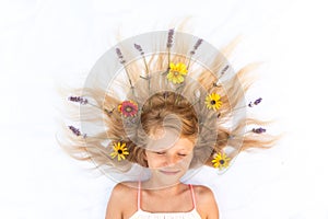 Cute child with long blond hair stylized with lavender and gerbera floral decoration, shot from birds perspective