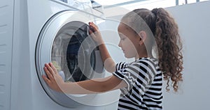 Cute child looks inside the washing machine. Cylinder spinning machine. Concept laundry washing machine, industry