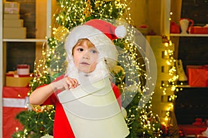 Cute child opening a Christmas present. Little Santa Claus helper with Christmas gift.