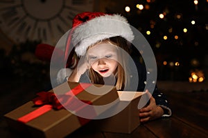 Cute child opening magic gift box near Christmas tree