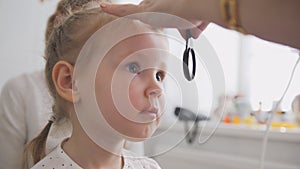 Cute child in ophthalmology clinic - optometrist diagnosis little blonde girl