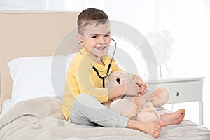 Cute child playing doctor with stuffed toy