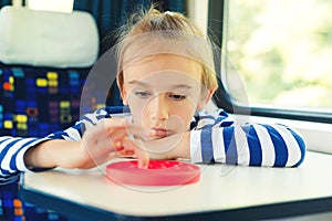 Cute child playing popit toy during travelling by train. Entertainment for young passenger