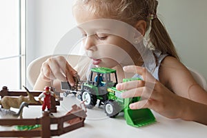 Cute child plays with farm equipment toys. Business or farming concept