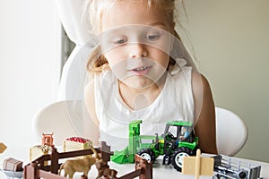 Cute child plays with farm equipment toys. Business or farming concept