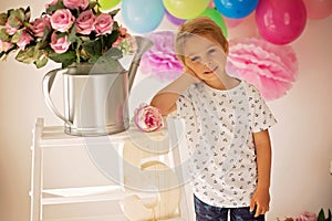 Cute child, preschool boy, celebrating birthday at home, holding number five wooden number, balloons and decoration