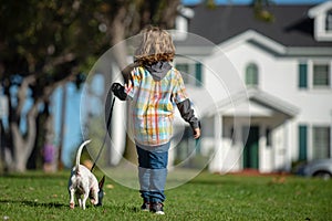 Cute child and puppy playing outside. Happy Kid boy and pet dog walking at backyard lawn.