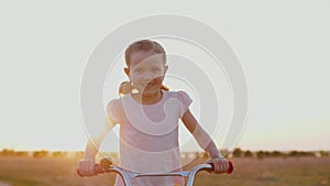 Cute child riding bicycle at sunset of golden sun, having fun outdoors on nature
