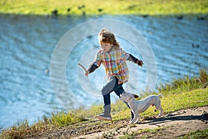 Cute child running with a puppy dog, outdoor summer.