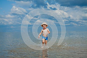 Cute child running from sea waves on beach