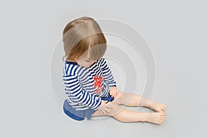 Cute child sitting on gray space looking down