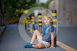 Cute child, sitting on the ground in the city, playing with little pet maltese dog