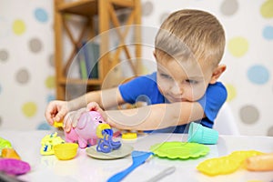 Cute child sitting at the table and plays with playdough