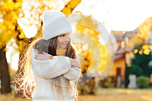 Cute child smiling and posing outdoors. Little girl wearing warm knitted sweater. Autumn kids fashion, lifestyle