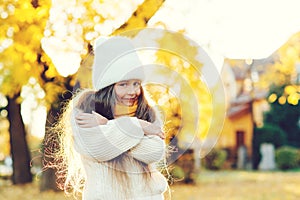 Cute child smiling and posing outdoors. Little girl wearing warm knitted sweater. Autumn kids fashion, lifestyle