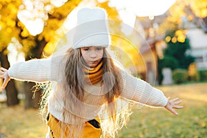 Cute child smiling and posing outdoors. Little girl wearing warm knitted sweater. Autumn kids fashion, lifestyle