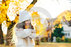 Cute child smiling and posing outdoors. Little girl wearing warm knitted sweater. Autumn kids fashion, lifestyle