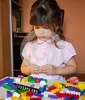 Cute child stacks building cubes sitting at table in nursery room