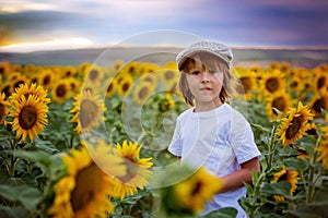 Cute child with sunflower in summer sunflower field on sunset.