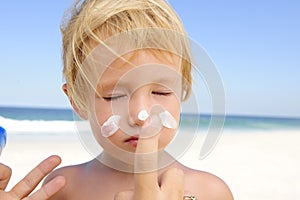 Cute child with sunscreen at the beach photo