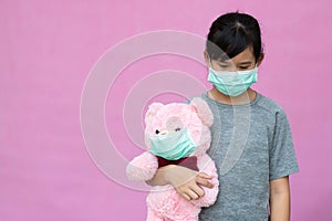 Cute child with teddy bear in wearing surgical mask.