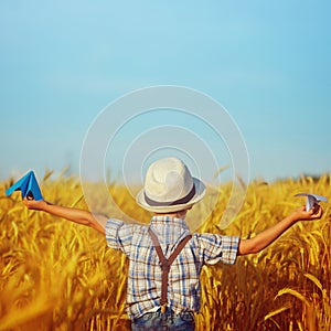 Cute child walking in the wheat golden field on a sunny summer day. Square.