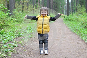 Cute child walks in the pine wood