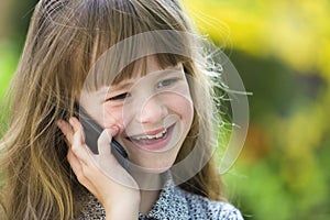 Cute child young girl talking on cellphone outdoors. Children and modern technology, communication concept