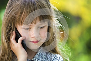 Cute child young girl talking on cellphone outdoors. Children and modern technology, communication concept