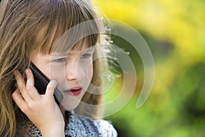 Cute child young girl talking on cellphone outdoors. Children and modern technology, communication concept