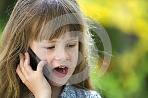 Cute child young girl talking on cellphone outdoors. Children and modern technology, communication concept