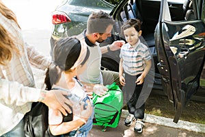 Cute children arriving to school with mom and dad