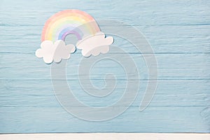 Cute children or baby background, white clouds with rainbow on the blue wooden background