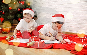 Cute children boys writes the letter to Santa Claus near Xmas tree