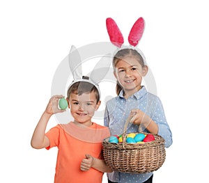 Cute children in bunny ears headbands holding basket with Easter eggs on white