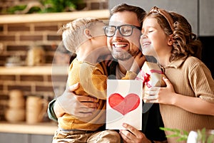 Cute children congratulating happy daddy with Fathers day and giving him handmade greeting postcard