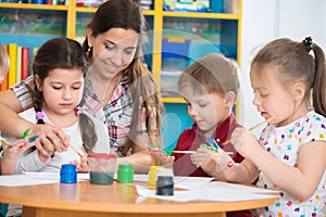 Cute children drawing with teacher at preschool class