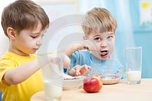 Cute children eat healthy food enjoying breakfast