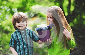 Cute children gardening and planting flowers to the ground in spring garden, seasonal outdoor activities, happy