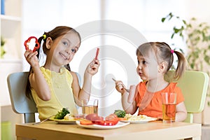 Cute children girls eating healthy food. Kids lunch at home or kindergarten.