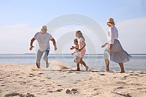 Cute children with grandparents spending time together on sea beach