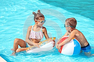 Cute children with inflatable toys in swimming pool