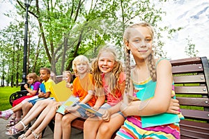 Cute children with notebooks sit on bench