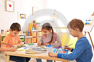 Cute children painting at table in room