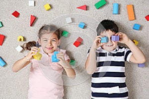 Cute children playing with colorful blocks on floor indoors