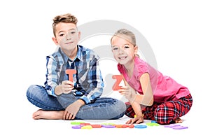 Cute children playing with large colorful alphabet letters on white background. Kids speech therapy concept.