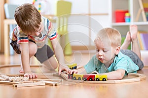 Cute children playing with wooden train. Toddler kids play with blocks and trains. Boys building toy railroad at home or